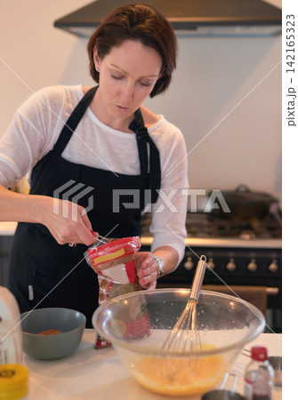 Woman, kitchen and baking in home, measure and ingredients for weekend activity. Food, pastry and cooking with recipe for hobby and fun, prepare and cake or baker in house for dessert or pudding 142165323