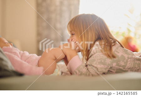 Family, feet and sister kissing baby girl on bed in home together for care, relationship or support. Bedroom, children and love with sibling kids bonding in apartment for child development or growth Family, feet and sister kissing baby girl on bed in home together for care, relationship or support. Bedroom, children and love with sibling kids bonding in apartment for child development or growth 142165585