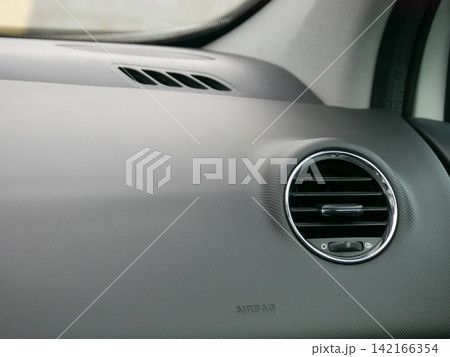 Close up view of car dashboard with air conditioning vent and airbag label. Interior detail of vehicle cockpit. Modern automobile design concept for automotive safety and comfort feature. Close up view of car dashboard with air conditioning vent and airbag label. Interior detail of vehicle cockpit. Modern automobile design concept for automotive safety and comfort feature. 142166354
