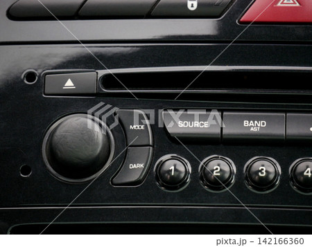 Car audio system control panel with radio buttons and volume knob. Dashboard console interface in vehicle interior. Automotive electronics technology and multimedia equipment equipment. Car audio system control panel with radio buttons and volume knob. Dashboard console interface in vehicle interior. Automotive electronics technology and multimedia equipment equipment. 142166360