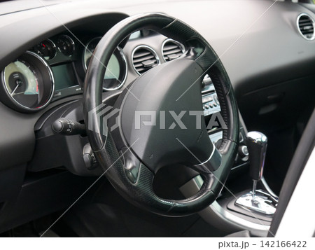 Car interior with steering wheel and dashboard view. Modern vehicle cockpit design. Automotive transport control system inside automobile. Driver seat perspective for travel lifestyle. Car interior with steering wheel and dashboard view. Modern vehicle cockpit design. Automotive transport control system inside automobile. Driver seat perspective for travel lifestyle. 142166422