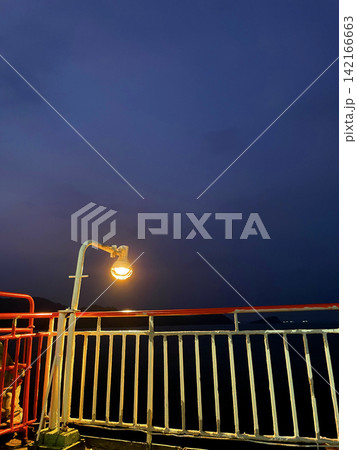 The illuminated ferry deck railing against the backdrop of a deep sunset sky The illuminated ferry deck railing against the backdrop of a deep sunset sky 142166663