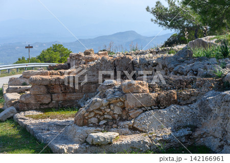 Ancient ruins overlook picturesque valley of lush greenery and distant mountains Ancient ruins overlook picturesque valley of lush greenery and distant mountains 142166961