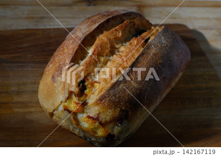 Freshly baked artisanal bread with a golden crust resting on a wooden board in a cozy kitchen setting during early morning hours Freshly baked artisanal bread with a golden crust resting on a wooden board in a cozy kitchen setting during early morning hours 142167119