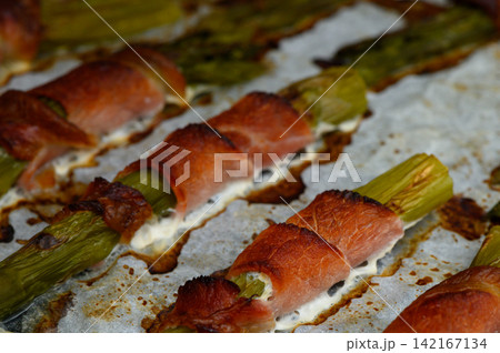 Delicious asparagus wrapped in savory meat, baked to perfection, ready for a delightful dining experience at home Delicious asparagus wrapped in savory meat, baked to perfection, ready for a delightful dining experience at home 142167134