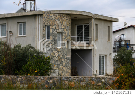 Modern stone facade villa surrounded by natural greenery under an overcast sky Modern stone facade villa surrounded by natural greenery under an overcast sky 142167135