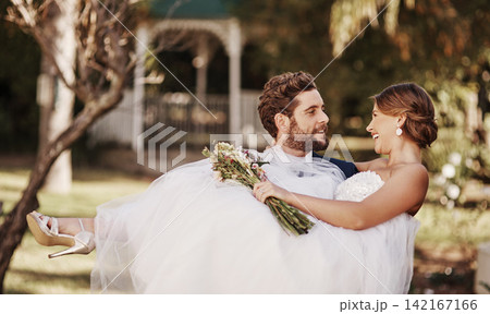 Wedding, couple and carrying woman in nature for love, protection and commitment at venue for celebration. Lifting bride, man and happy in garden for marriage, partnership and support with flowers Wedding, couple and carrying woman in nature for love, protection and commitment at venue for celebration. Lifting bride, man and happy in garden for marriage, partnership and support with flowers 142167166