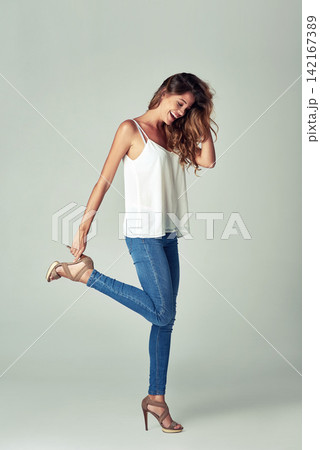 Happy, woman and denim for fashion in studio with stylish, glamour and elegant by posing in heels. Confident, female person and creative clothing with attractive beauty poses on white background Happy, woman and denim for fashion in studio with stylish, glamour and elegant by posing in heels. Confident, female person and creative clothing with attractive beauty poses on white background 142167389