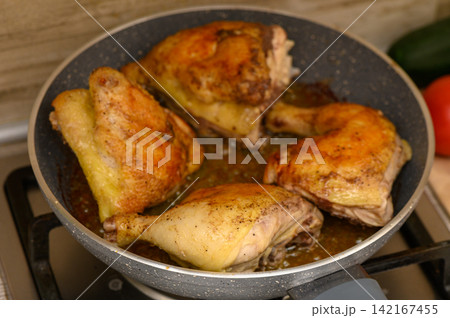Golden chicken thighs sizzling in a skillet on a sunny kitchen counter Golden chicken thighs sizzling in a skillet on a sunny kitchen counter 142167455