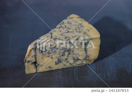 Delicious wedge of blue cheese resting on a rustic wooden board 142167653