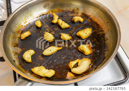 Burnt Food Remnants in Frying Pan on Stovetop 142167765