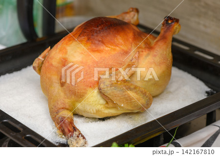 Golden roasted chicken resting on a bed of salt, ready for a delicious feast Golden roasted chicken resting on a bed of salt, ready for a delicious feast 142167810