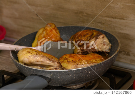 Sizzling chicken pieces cooked to perfection in a frying pan on a cozy kitchen stove 142167860