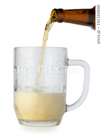 Pouring beer from a brown bottle into a wet, condensation-covered glass mug on a white background Pouring beer from a brown bottle into a wet, condensation-covered glass mug on a white background 142168680