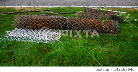 Old Wire Fencing Rolls Lie on Green Grass Old Wire Fencing Rolls Lie on Green Grass 142168940