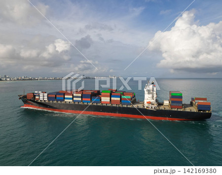 Aerial view cargo ship entering harbor. Cargo business. Container ship. Shipping logistics. Cargo ship in sea, aerial view. Freight container loaded on cargo vessel. Freight containers stacked high Aerial view cargo ship entering harbor. Cargo business. Container ship. Shipping logistics. Cargo ship in sea, aerial view. Freight container loaded on cargo vessel. Freight containers stacked high 142169380