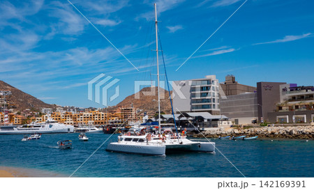 Cabo San Lucas, Mexico - May 15, 2019: Catamaran sailing in sea. Luxury catamaran yacht in bay. Summer vacation. Luxury travel life. Vacation on summer. Catamaran at sea with tourists. Sea travel Cabo San Lucas, Mexico - May 15, 2019: Catamaran sailing in sea. Luxury catamaran yacht in bay. Summer vacation. Luxury travel life. Vacation on summer. Catamaran at sea with tourists. Sea travel 142169391