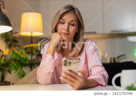 Adult woman scrolls news on smartphone bored tired stressed demotivated seeks calm break at night Adult woman scrolls news on smartphone bored tired stressed demotivated seeks calm break at night 142170396