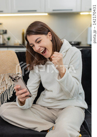 Happy woman celebrates finance app balance rise on smartphone makes victory fist, win victory game 142170431
