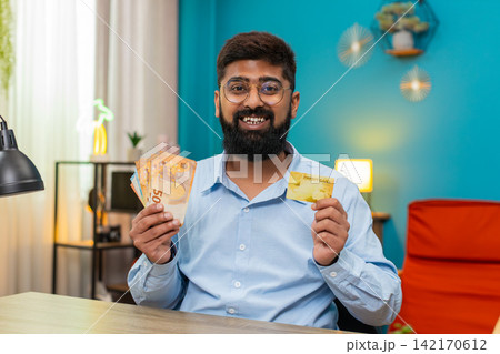 Indian man showing credit card with euro money cash offering withdrawal loan financial offer at home 142170612