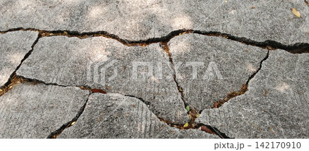 Cracked concrete pavement with sunlight and shadows. 142170910