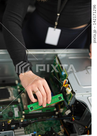 Female IT technician in her 30s upgrades a server with a new PCIe expansion card Female IT technician in her 30s upgrades a server with a new PCIe expansion card 142171296