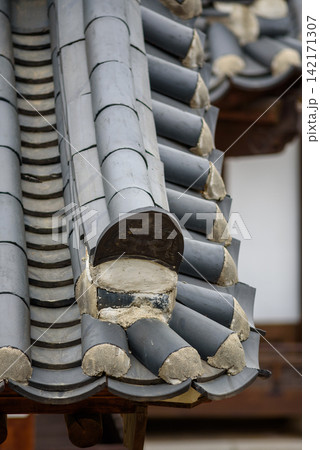 A detailed close-up photograph of an East Asian temple roof with intricate dark gray tiles arranged in repeating patterns 142171307