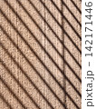 Diagonal shadows casting pattern on textured wall 142171446