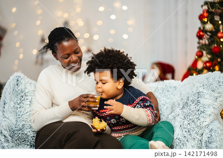 Mother and son enjoying Christmas celebration with juice and snack Mother and son enjoying Christmas celebration with juice and snack 142171498