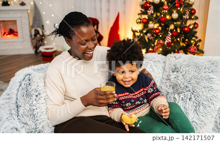 Mother and son celebrating holiday with juice and donut Mother and son celebrating holiday with juice and donut 142171507