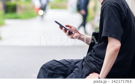 街中でスマホを見る若い男性 街中でスマホを見る若い男性 142171763