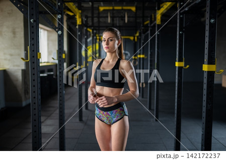 Young woman standing between training racks in a gym Young woman standing between training racks in a gym 142172237