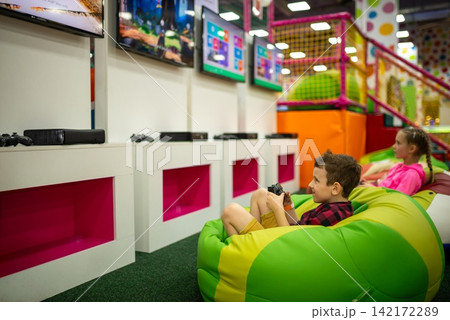 Children holding controllers and playing video games in bean bag chairs Children holding controllers and playing video games in bean bag chairs 142172289