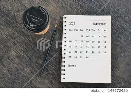 September 2026 desk calendar with disposable coffee cup and pen on wooden table. Directly above. Flat lay September 2026 desk calendar with disposable coffee cup and pen on wooden table. Directly above. Flat lay 142172429