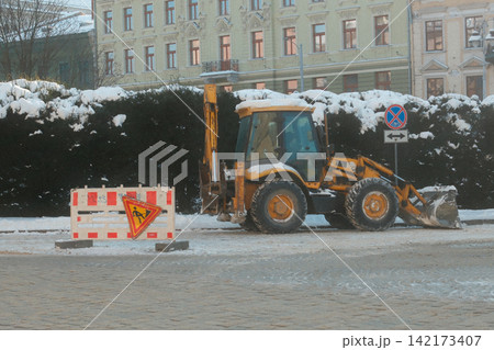 Yellow tractor parked on a snowy city street during winter season Yellow tractor parked on a snowy city street during winter season 142173407