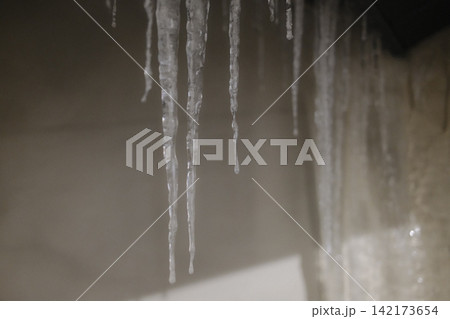 Sharp icicles hanging from a roof during a cold winter day 142173654