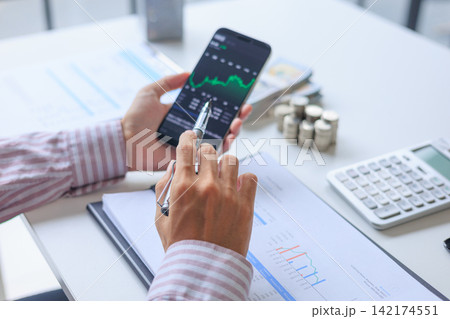 Businessman monitoring real-time stock portfolio and financial reports at office desk. Businessman monitoring real-time stock portfolio and financial reports at office desk. 142174551