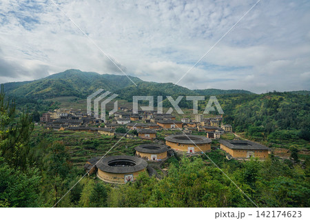 Fujian Tulou Village in Green Mountains Under Cloudy Sky Fujian Tulou Village in Green Mountains Under Cloudy Sky 142174623