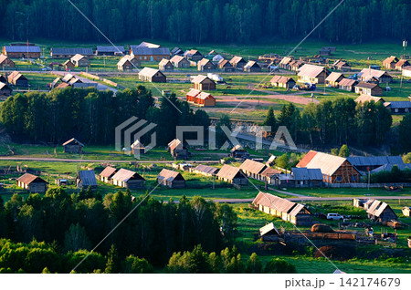 Rural Village with Wooden Cabins in Green Forest Valley 142174679