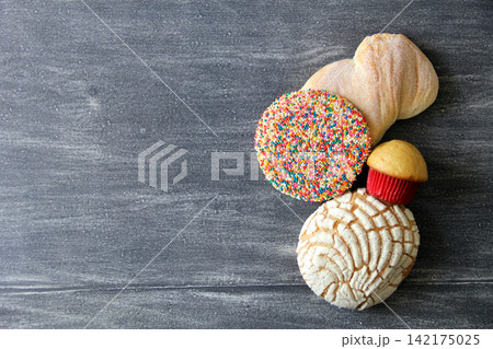 Mexican bakery, sweet bread on vintage gray table: shell, cupcake, bow tie, ear, biscuit with multicolored sprinkles Mexican bakery, sweet bread on vintage gray table: shell, cupcake, bow tie, ear, biscuit with multicolored sprinkles 142175025