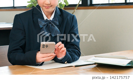 家でスマホを使って勉強,宿題,リビング学習する中学生,高校生,小学生,生徒の女の子 家でスマホを使って勉強,宿題,リビング学習する中学生,高校生,小学生,生徒の女の子 142175757