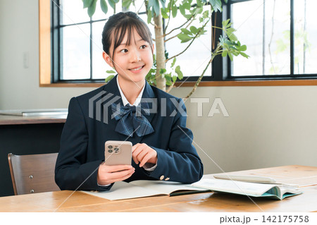 家でスマホを使って勉強,宿題,リビング学習する中学生,高校生,小学生,生徒の女の子 家でスマホを使って勉強,宿題,リビング学習する中学生,高校生,小学生,生徒の女の子 142175758