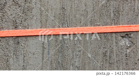 Bright orange ropes run across the rough gray concrete walls. Bright orange ropes run across the rough gray concrete walls. 142176366
