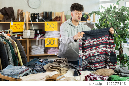 Young man chooses sweater in clothing store 142177148