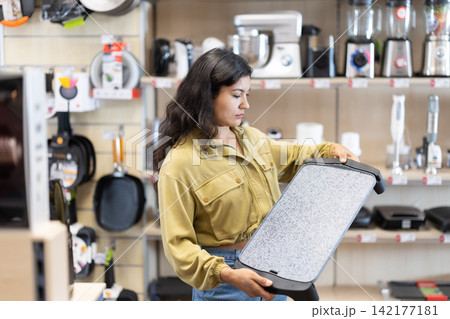 Female shopper selects an electric griddle at hardware store Female shopper selects an electric griddle at hardware store 142177181