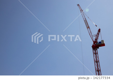 Construction crane lifts materials high above a bustling city Construction crane lifts materials high above a bustling city 142177334