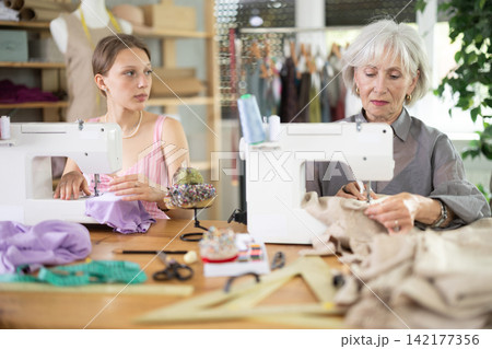 Elderly and young women seamstresses sewing on machine 142177356