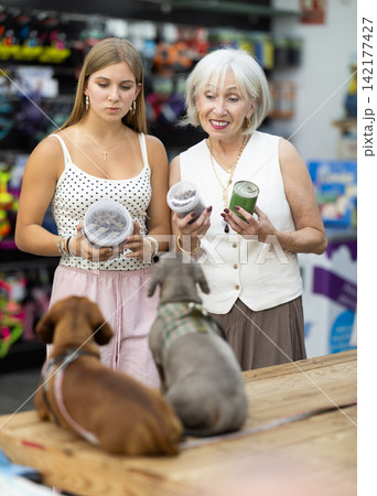 elderly woman stands in a pet store with a teenage girl and chooses food elderly woman stands in a pet store with a teenage girl and chooses food 142177427