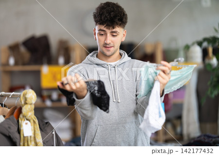 Young man chooses female panties in clothing store Young man chooses female panties in clothing store 142177432