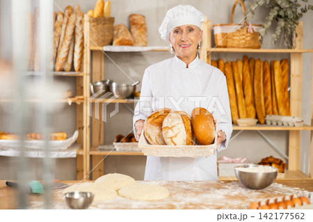 Senior female baker worker show loafs of breads Senior female baker worker show loafs of breads 142177562